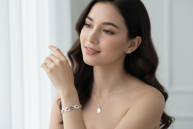 A bright, elegant portrait of a young woman wearing a timeless silver bracelet on her wrist, paired with a delicate silver necklace and small silver earrings. 